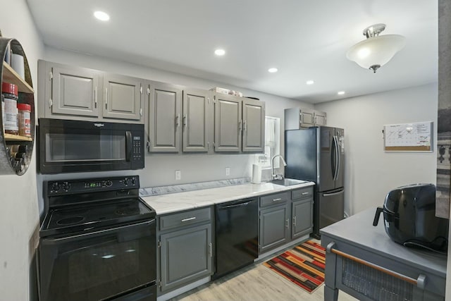 kitchen featuring sink, light wood-type flooring, black appliances, and gray cabinets