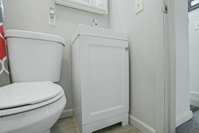 bathroom with toilet, vanity, and hardwood / wood-style floors