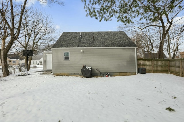 snow covered back of property featuring central AC unit