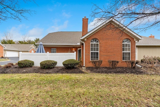 exterior space featuring a lawn, a chimney, roof with shingles, fence, and brick siding