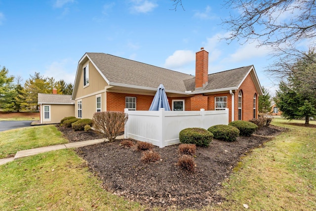 view of property exterior with a shingled roof, brick siding, fence, and a chimney