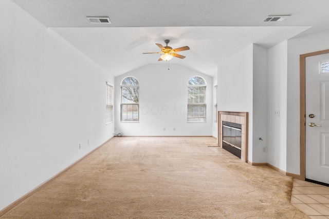 unfurnished living room with lofted ceiling, light carpet, a textured ceiling, a tile fireplace, and ceiling fan