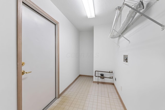 clothes washing area featuring laundry area, baseboards, washer hookup, and a textured ceiling