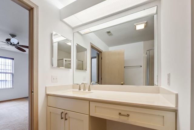 bathroom with vanity, ceiling fan, and walk in shower