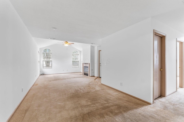 unfurnished living room featuring lofted ceiling, light colored carpet, a textured ceiling, and ceiling fan