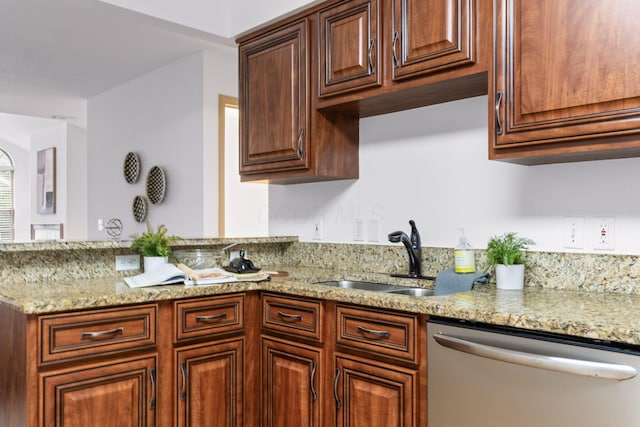 kitchen featuring dishwasher, a peninsula, light stone counters, and a sink