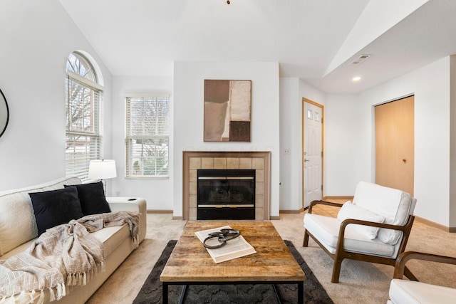 carpeted living room with vaulted ceiling, a tiled fireplace, visible vents, and baseboards