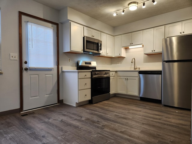 kitchen featuring white cabinets, dark hardwood / wood-style floors, stainless steel appliances, and a textured ceiling