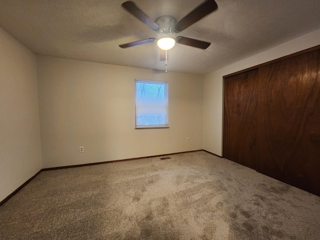 unfurnished bedroom featuring ceiling fan, a textured ceiling, a closet, and carpet floors