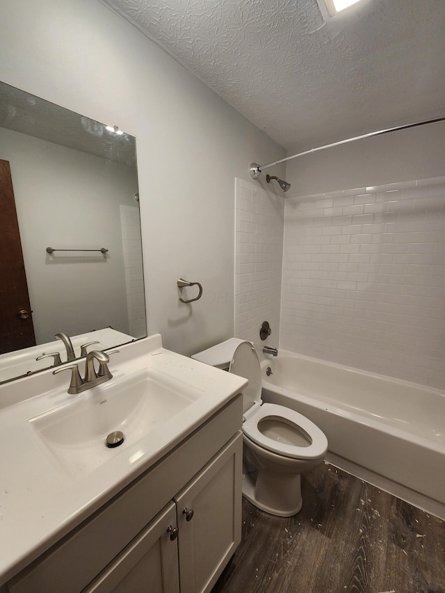 full bathroom featuring toilet, vanity, wood-type flooring, a textured ceiling, and bathtub / shower combination