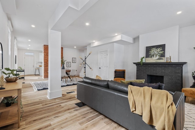 living room featuring light hardwood / wood-style flooring and a brick fireplace