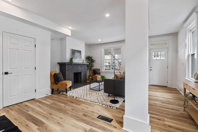 interior space with a brick fireplace and light hardwood / wood-style floors