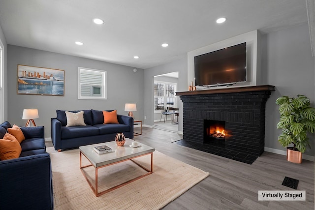 living room featuring light hardwood / wood-style floors and a brick fireplace