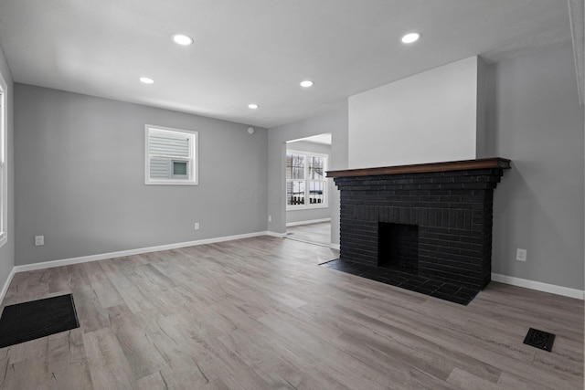 unfurnished living room featuring a fireplace and light hardwood / wood-style flooring