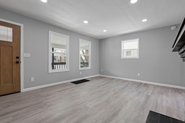 foyer entrance with a fireplace and light wood-type flooring