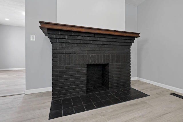 interior details with wood-type flooring and a brick fireplace