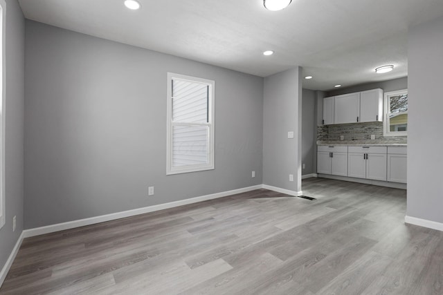 kitchen with white cabinetry, light wood-type flooring, and backsplash