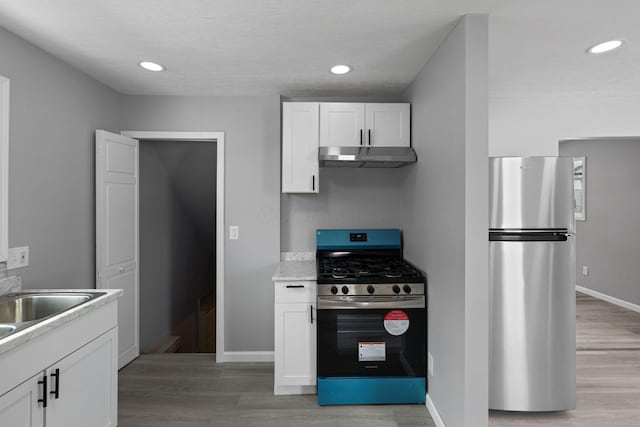 kitchen featuring white cabinets, light wood-type flooring, appliances with stainless steel finishes, and sink