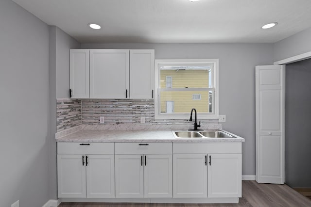 kitchen with white cabinets, light hardwood / wood-style flooring, tasteful backsplash, and sink