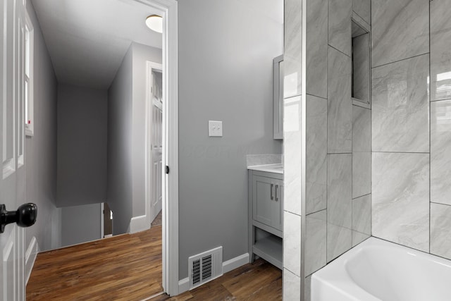 bathroom with hardwood / wood-style floors,  shower combination, and vanity