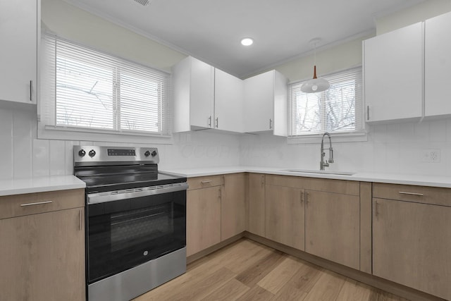 kitchen with stainless steel range with electric cooktop, white cabinets, tasteful backsplash, and sink