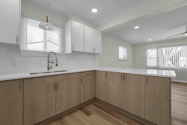 kitchen with a healthy amount of sunlight, backsplash, kitchen peninsula, and sink