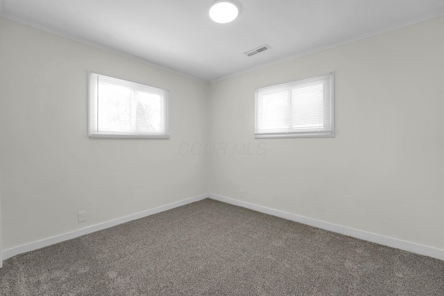 empty room featuring crown molding and dark colored carpet