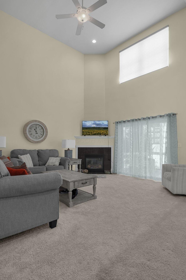 carpeted living room with a fireplace and ceiling fan