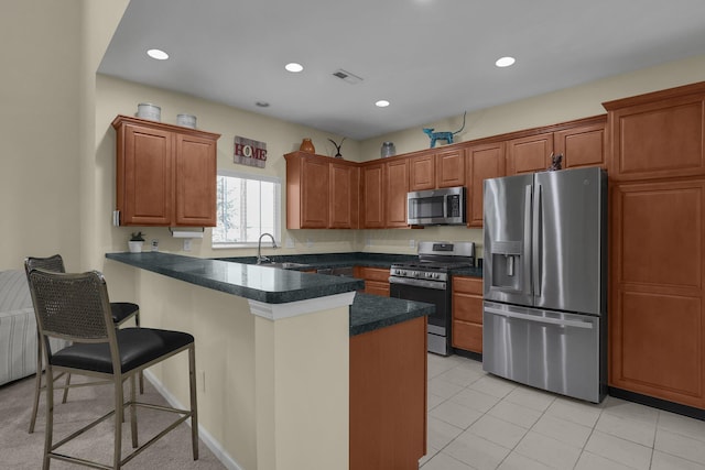 kitchen featuring appliances with stainless steel finishes, a kitchen bar, sink, kitchen peninsula, and light tile patterned floors