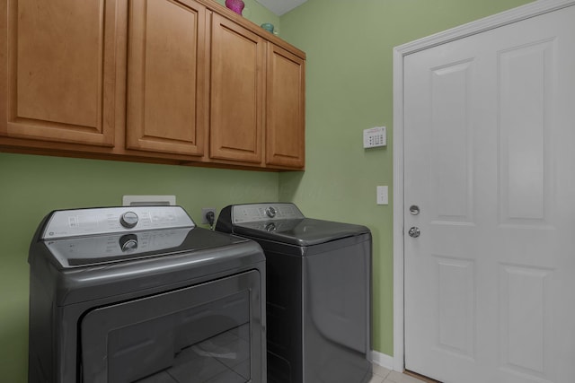 laundry room featuring washer and dryer, cabinets, and light tile patterned flooring