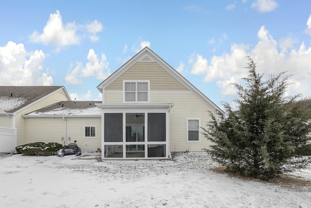 snow covered rear of property with a sunroom