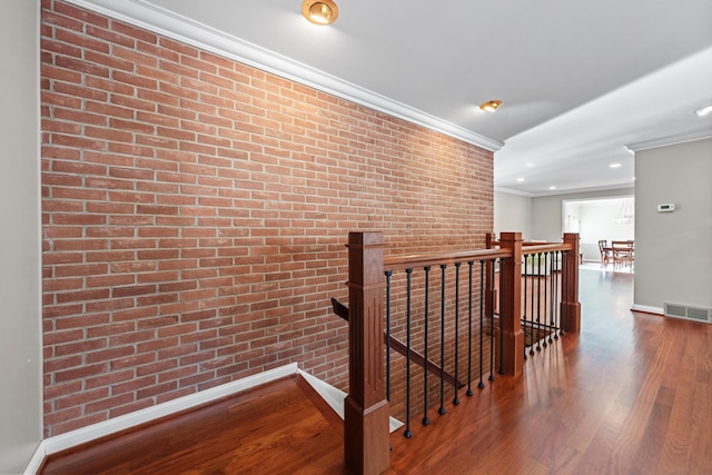 hall featuring wood-type flooring, brick wall, and crown molding