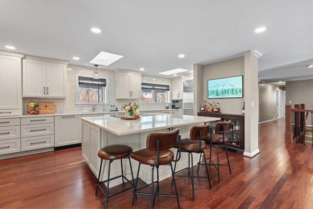 kitchen featuring a center island, a kitchen bar, a skylight, sink, and dark hardwood / wood-style floors