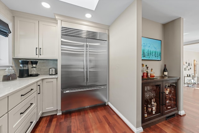 kitchen with wine cooler, dark hardwood / wood-style floors, built in fridge, and white cabinetry