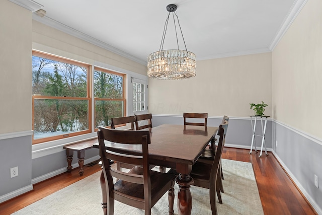 dining space featuring dark wood-type flooring, crown molding, and a chandelier