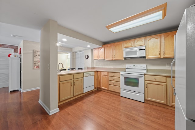 kitchen with sink, light brown cabinetry, light hardwood / wood-style floors, and white appliances