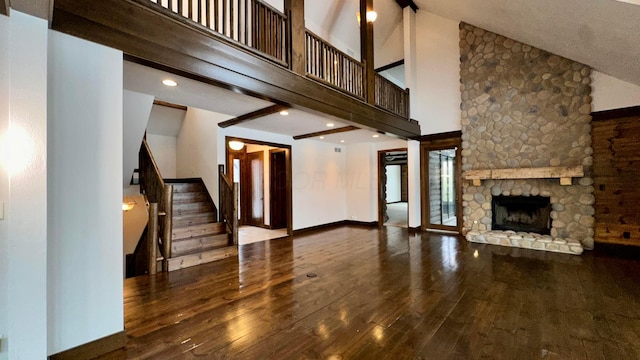 unfurnished living room featuring hardwood / wood-style flooring, a high ceiling, beamed ceiling, and a fireplace