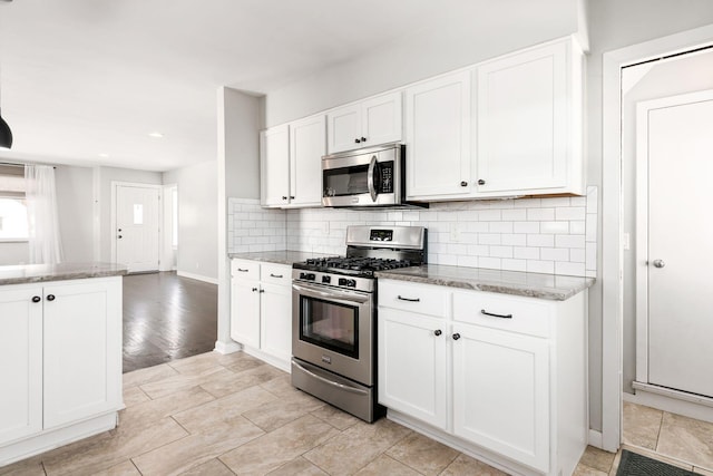 kitchen featuring appliances with stainless steel finishes, light hardwood / wood-style floors, white cabinets, and light stone countertops