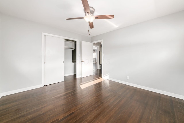 unfurnished bedroom with dark wood-type flooring, ceiling fan, a closet, and an AC wall unit