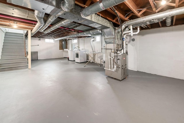 basement featuring heating unit, separate washer and dryer, and electric panel