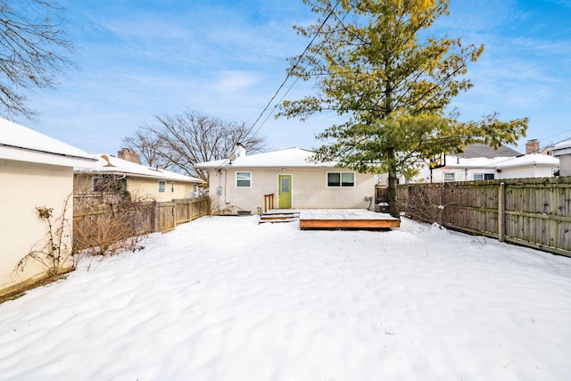 snow covered back of property featuring a wooden deck