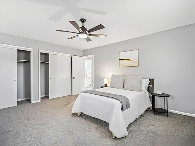 carpeted bedroom with ceiling fan and two closets