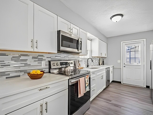 kitchen featuring a wealth of natural light, white cabinets, appliances with stainless steel finishes, and sink