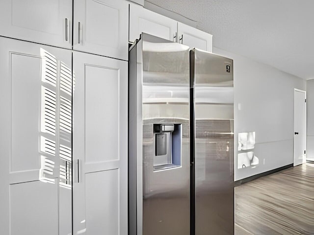 kitchen featuring wood-type flooring, white cabinets, and stainless steel fridge