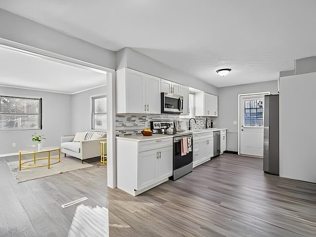 kitchen with white cabinets, backsplash, stainless steel appliances, and hardwood / wood-style flooring