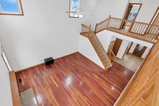 stairs featuring a ceiling fan, wood finished floors, baseboards, and a towering ceiling