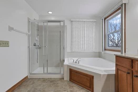 full bathroom featuring a bath, a shower stall, and vanity