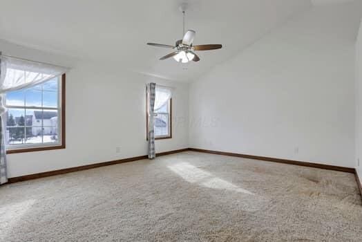 unfurnished room featuring lofted ceiling, carpet, baseboards, and ceiling fan