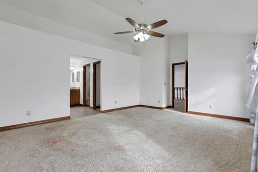 carpeted empty room featuring vaulted ceiling, baseboards, and ceiling fan