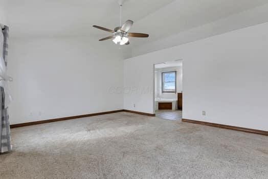 carpeted spare room featuring baseboards, a ceiling fan, and vaulted ceiling